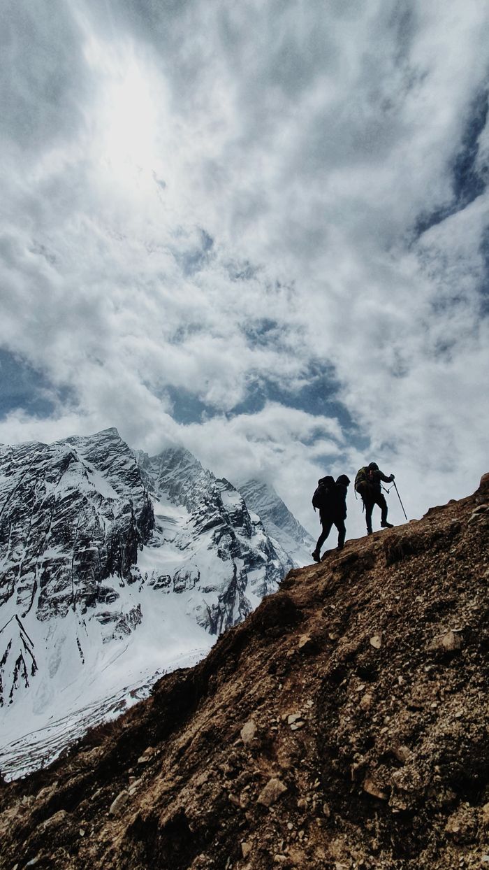 Two hikers trek along a snowy mountain in Nepal's scenic landscape.